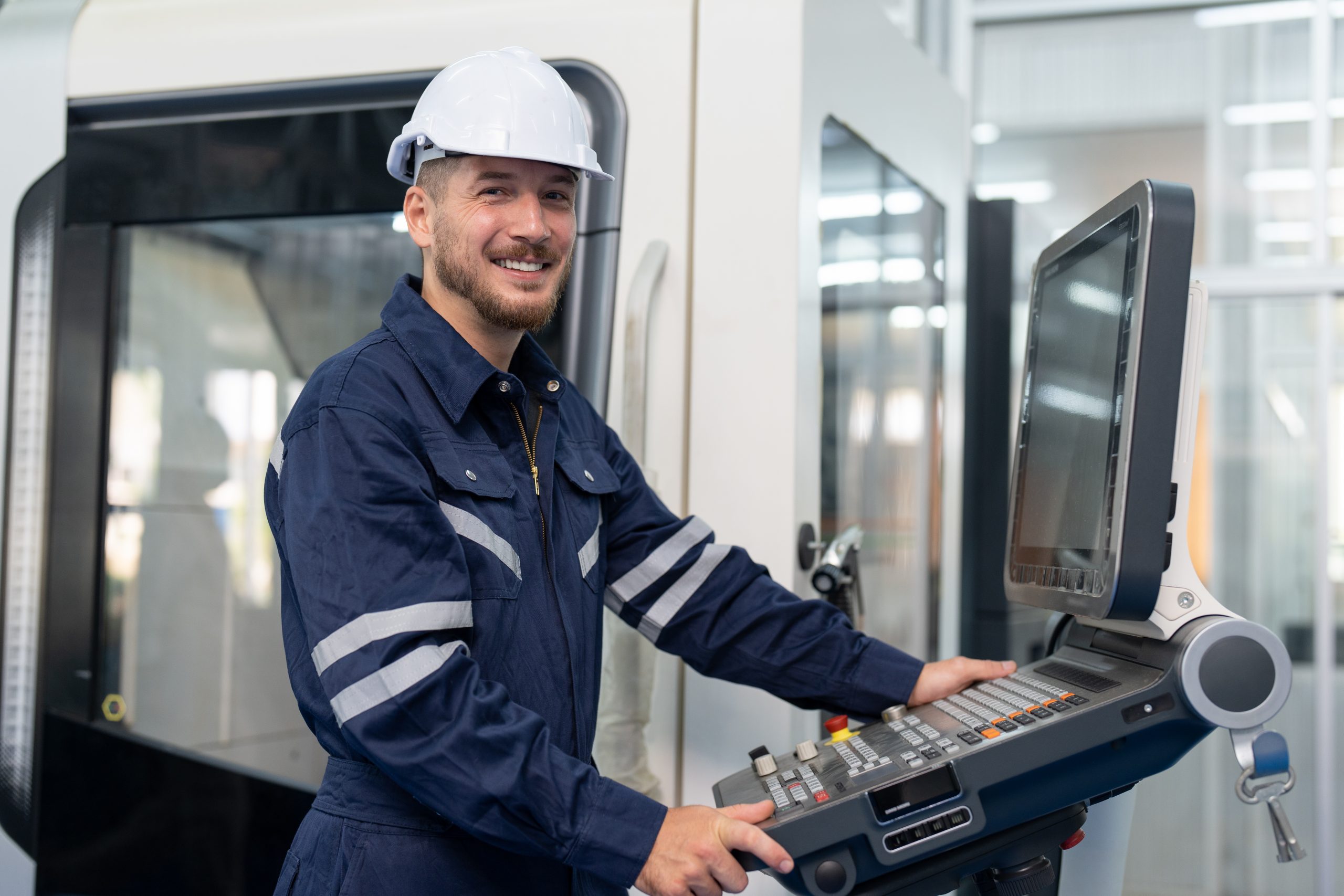 Lächelnder Techniker in Uniform und Helm arbeitet in der Werkstatt Schwermetall Industrie